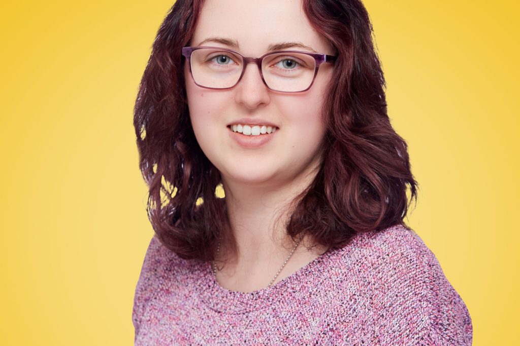 Jess smiling against a yellow background