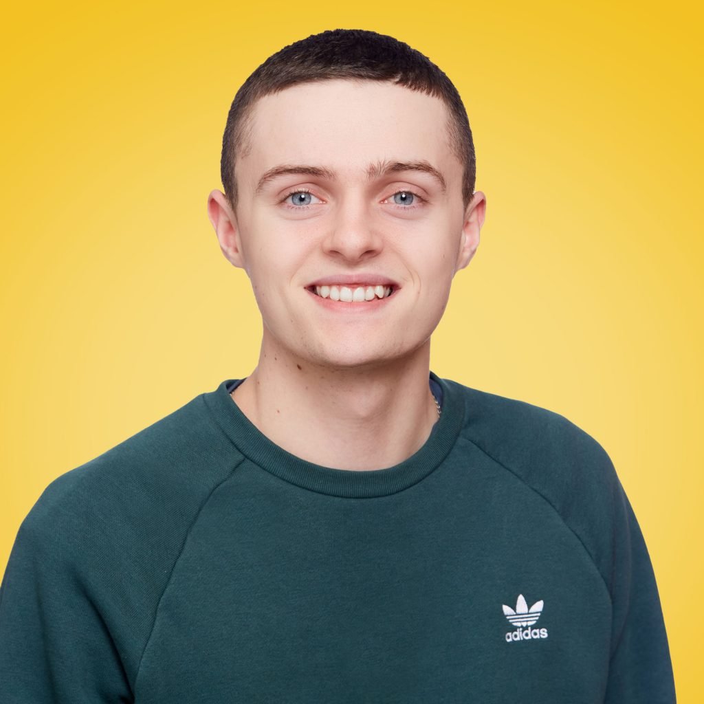 A smiling Pat pictured in from of a yellow background