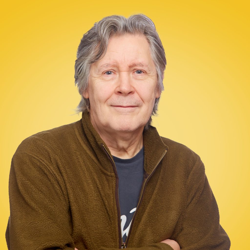 Tim with folded arms pictured against a yellow background