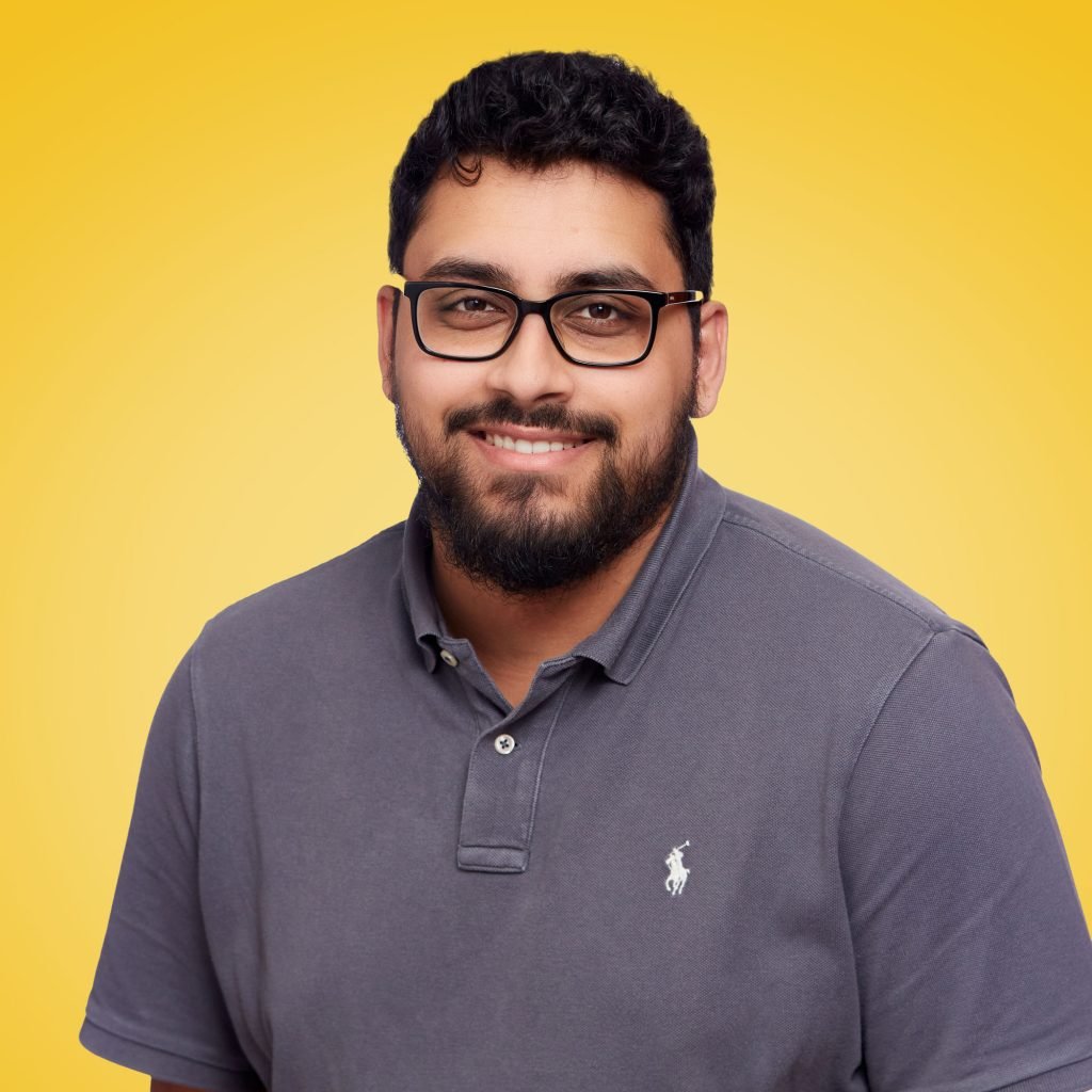 Zahir in a grey EPIX shirt pictured smiling against a yellow background