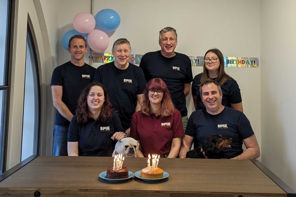 A photo showing some of the EPIX team with two birthday cakes, balloons and Happy Birthday bunting