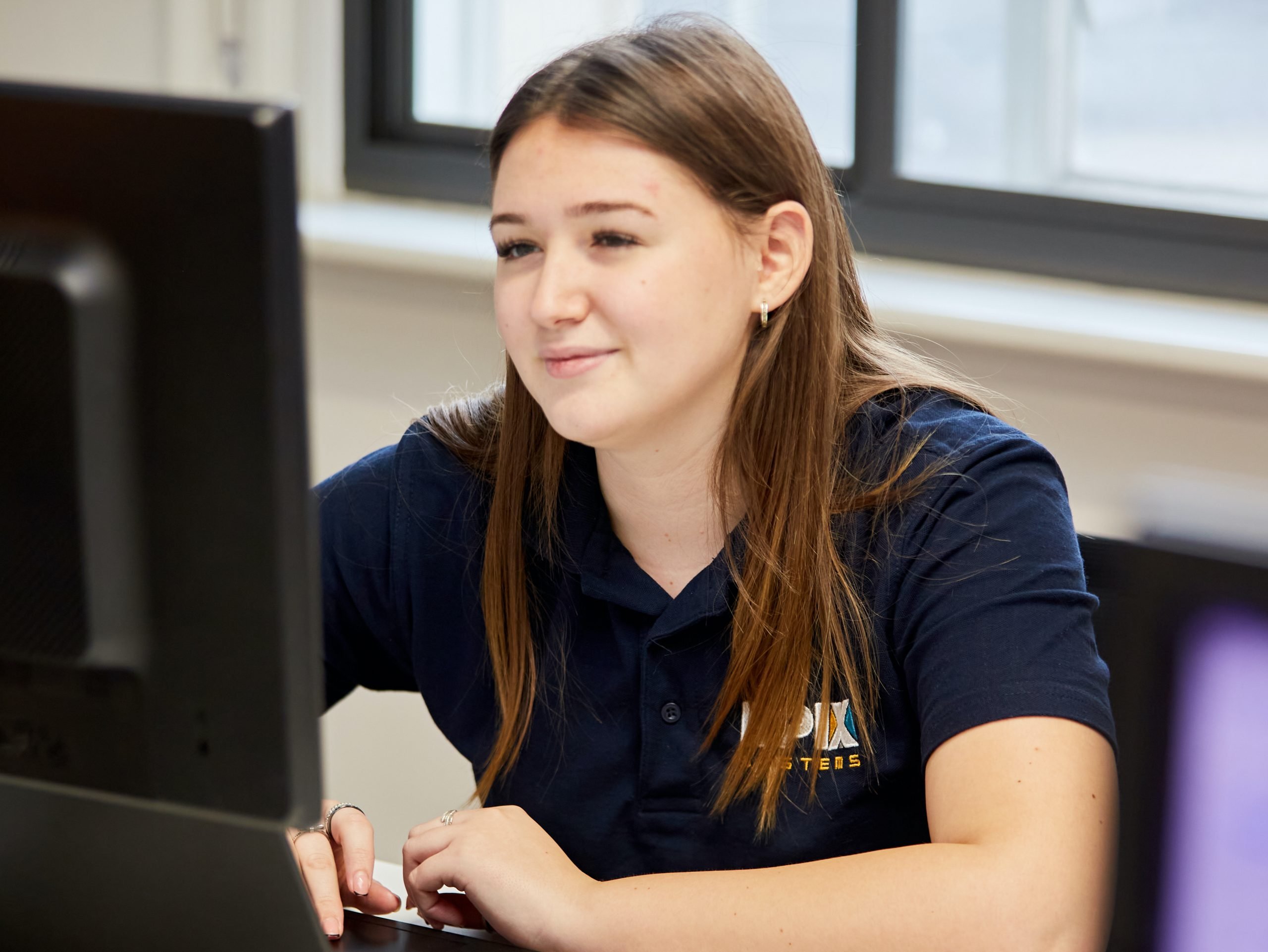 A photo of Ella at a computer in the EPIX offices